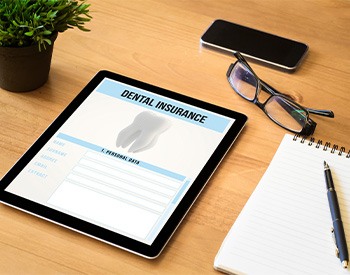 Dental insurance form on tablet with desk supplies