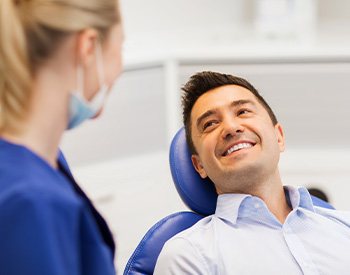 Patient in treatment chair smiling at dental assistant