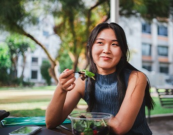 Girl smiling while eating lunch outside