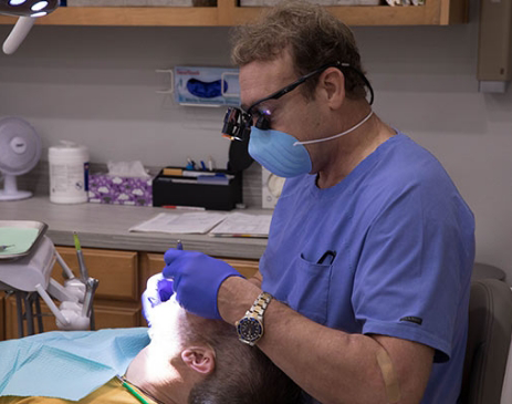 Male dentist with mask treating a patient