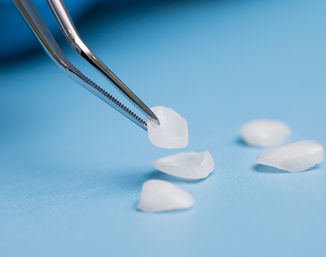 Metal instrument being used to pick up veneers