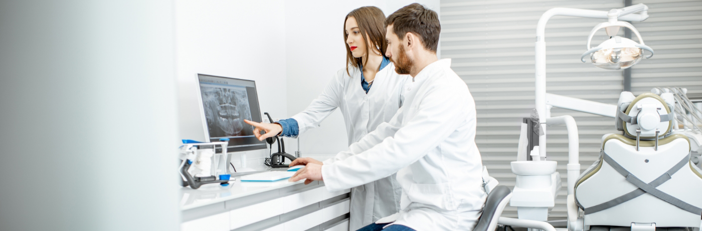 Two dentists looking at X-ray of teeth on computer screen