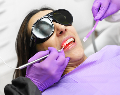 Woman with sunglasses receiving dental treatment with soft tissue laser