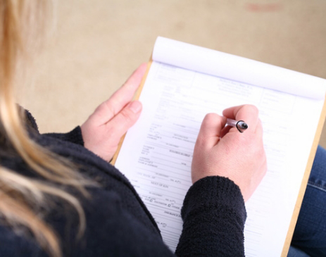 Close-up of woman writing on a notepad