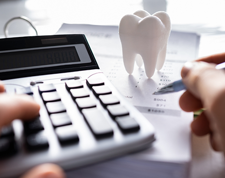 Calculator, hand holding pen, and tooth-shaped paperweight