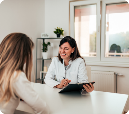 Female dentist with clipboard at counter talking to female patient