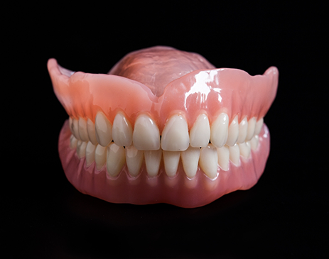 Close-up of full dentures against black background