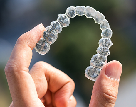 Close-up of hand holding Invisalign clear aligner