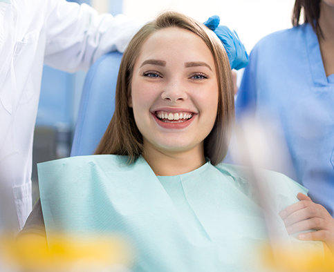 Blonde female patient sitting in dental chair and smiling