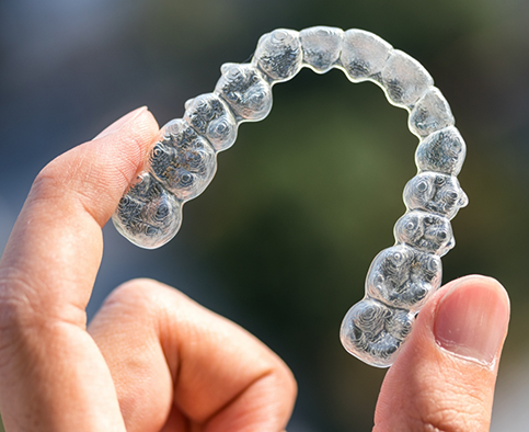 Close-up of hand holding a clear aligner