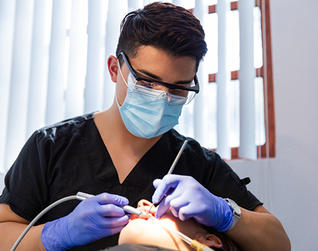 Dentist with glasses and mask performing oral cancer screening