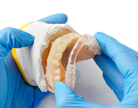 Gloved hands removing oral appliance from model of teeth