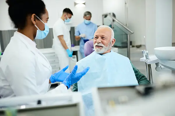 Older patient sitting in dental chair calmly discussing his questions about dental implants with dentist at Harper Dental in Fort Smith, AR