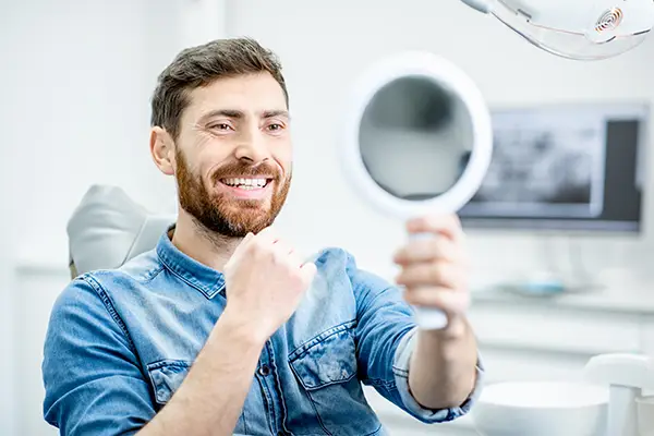 Bearded patient checking out his handsome smile in a mirror after root canal procedure at Harper Dental in Fort Smith, AR